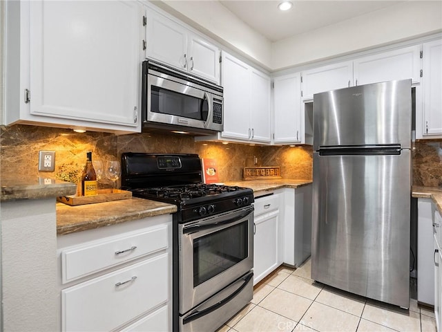 kitchen featuring decorative backsplash, appliances with stainless steel finishes, light tile patterned flooring, and white cabinets