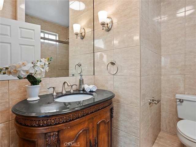 bathroom featuring vanity, tile walls, and toilet