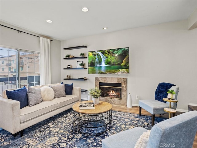 living room featuring recessed lighting, a premium fireplace, baseboards, and wood finished floors