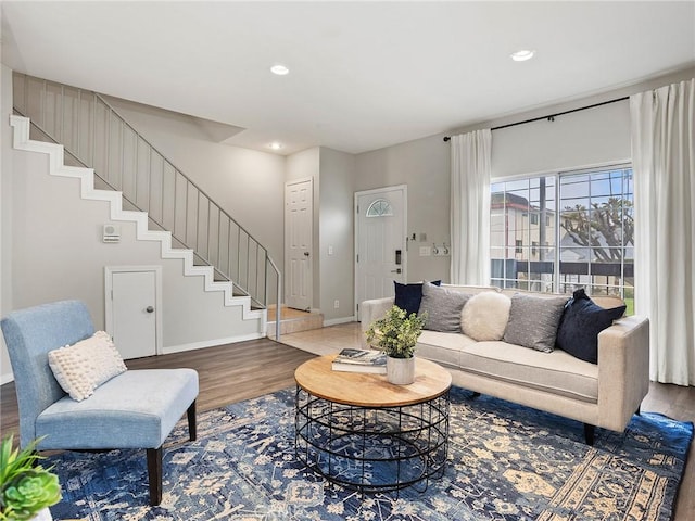 living area with recessed lighting, stairway, baseboards, and wood finished floors