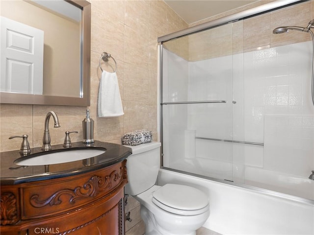 full bathroom featuring vanity, tile walls, toilet, combined bath / shower with glass door, and backsplash