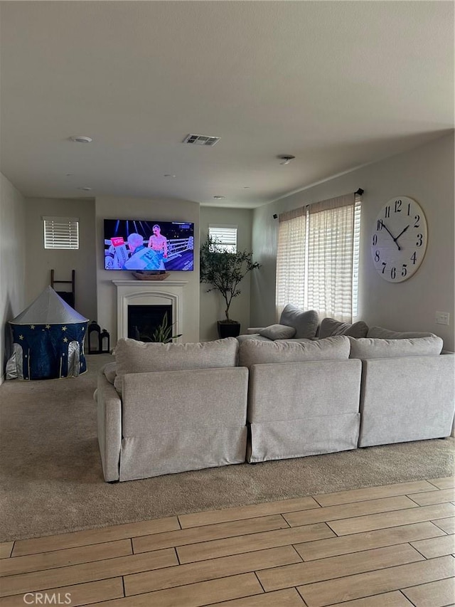 living room featuring visible vents, a fireplace, and wood finished floors