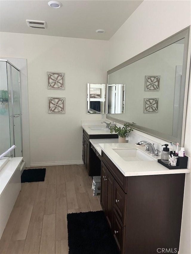 bathroom with visible vents, baseboards, a stall shower, wood finished floors, and vanity