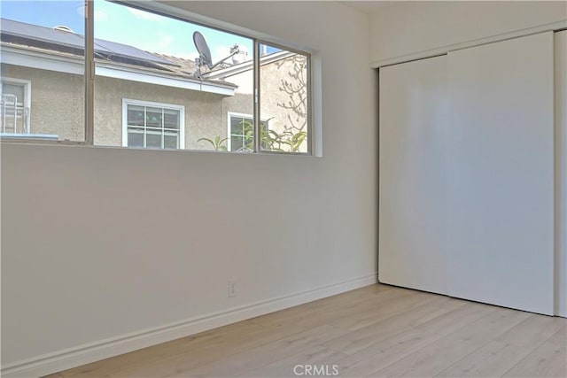 unfurnished room featuring baseboards and light wood-type flooring