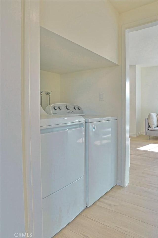 clothes washing area with light wood-style flooring, laundry area, and washer and clothes dryer