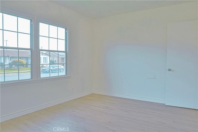 spare room featuring light wood finished floors and baseboards