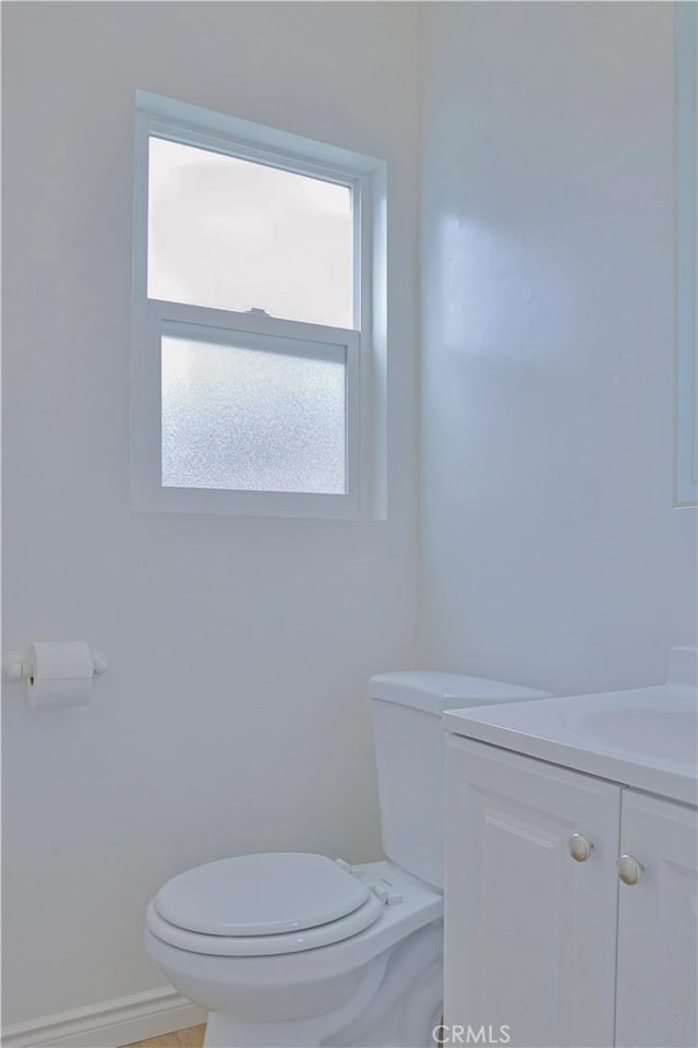 bathroom featuring toilet, vanity, and baseboards