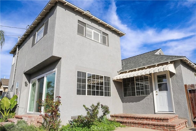 exterior space featuring stucco siding and roof with shingles