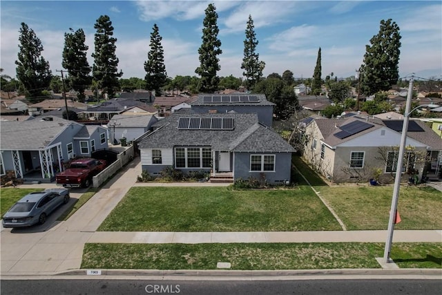 traditional-style house with a residential view, a front lawn, and roof mounted solar panels