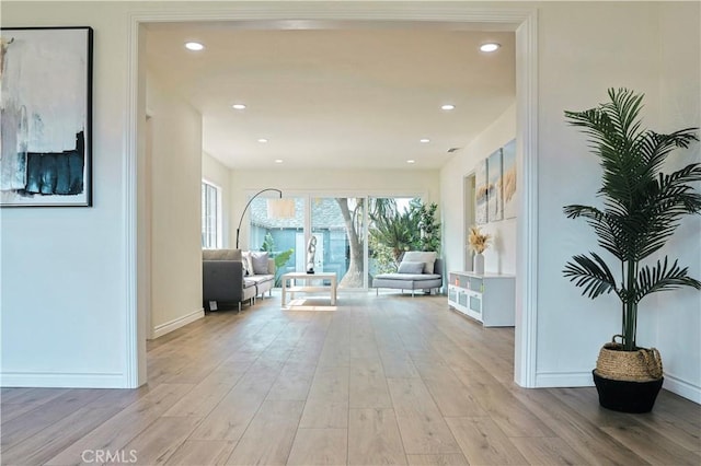 corridor with light wood-style flooring, recessed lighting, and baseboards