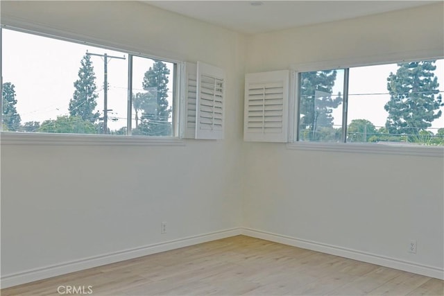 spare room with baseboards and wood finished floors