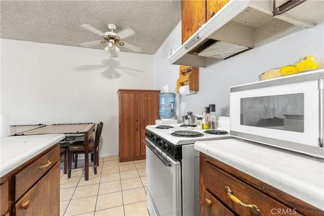 kitchen featuring light tile patterned floors, white appliances, a textured ceiling, and light countertops