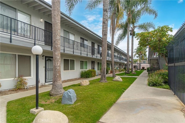 view of property's community with stairs and a lawn