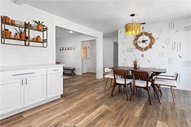 dining area featuring crown molding, light wood-type flooring, and baseboards