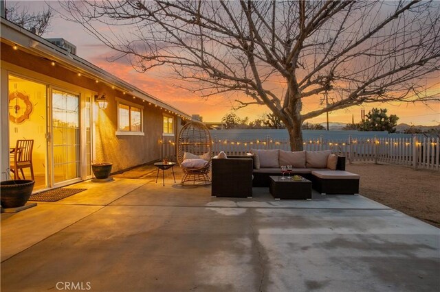 patio terrace at dusk featuring an outdoor living space and fence