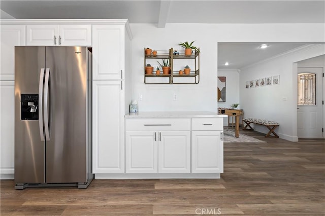 kitchen with dark wood-type flooring, white cabinets, light countertops, beamed ceiling, and stainless steel fridge