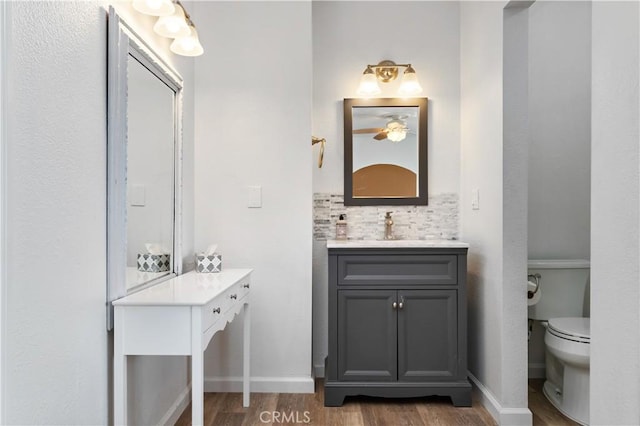 56838 Bonanza Dr, Yucca Valley, CA 92284 - bathroom featuring vanity, wood finished floors, toilet, baseboards, and decorative backsplash