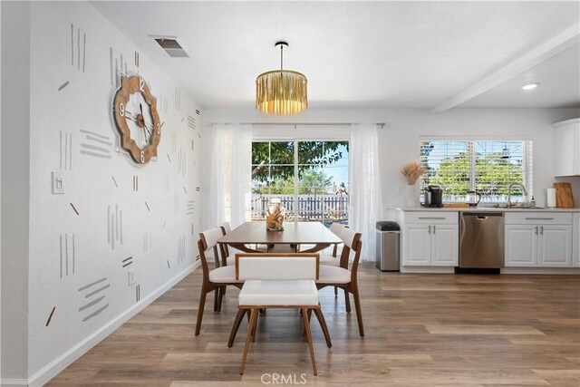 dining room featuring visible vents, baseboards, light wood-style floors, and beam ceiling