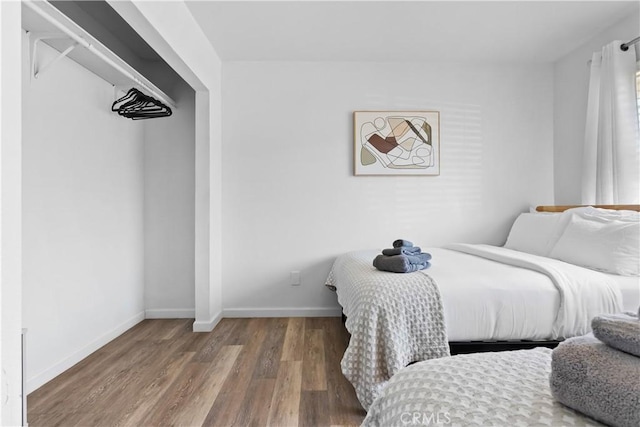 bedroom with baseboards and wood finished floors