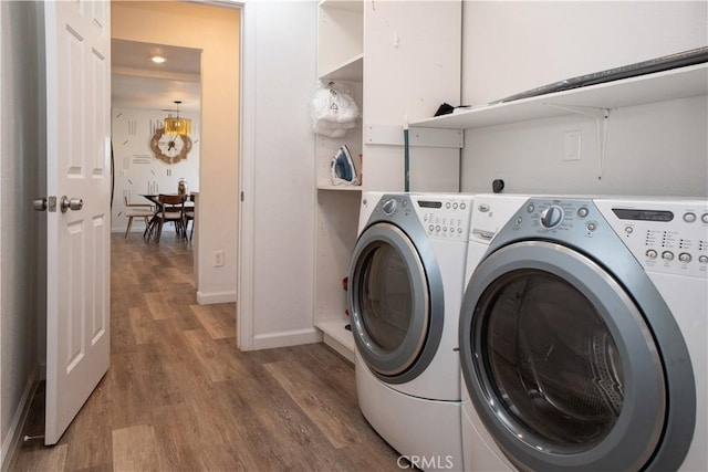 laundry area with laundry area, wood finished floors, baseboards, and washing machine and clothes dryer