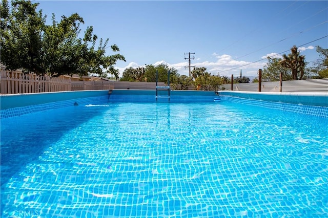 view of swimming pool featuring an infinity pool and fence