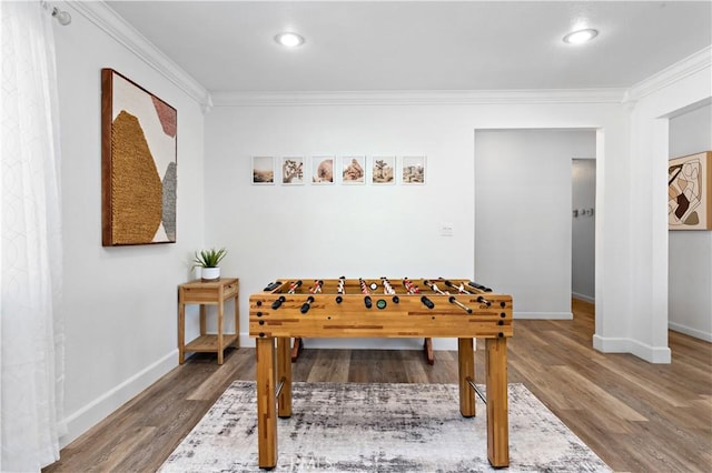 rec room with wood finished floors, baseboards, and ornamental molding