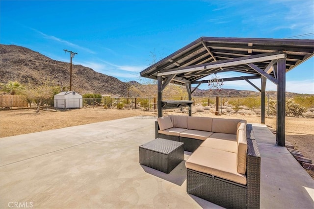 view of patio / terrace with a gazebo, an outdoor hangout area, a fenced backyard, an outbuilding, and a mountain view