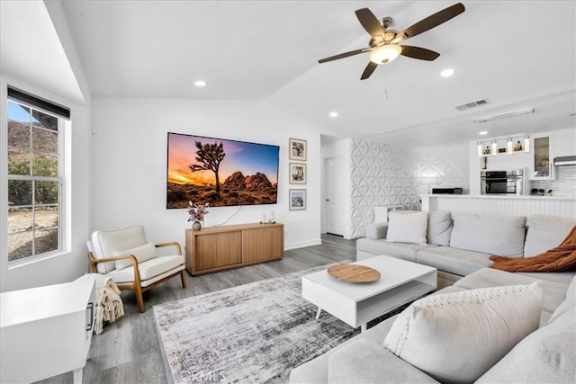 living room with visible vents, wood finished floors, and vaulted ceiling