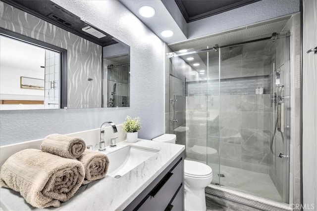 full bath featuring vanity, a stall shower, ornamental molding, toilet, and a textured wall