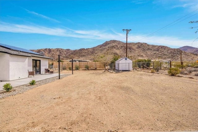 view of yard with a storage shed, a patio area, a mountain view, and an outdoor structure