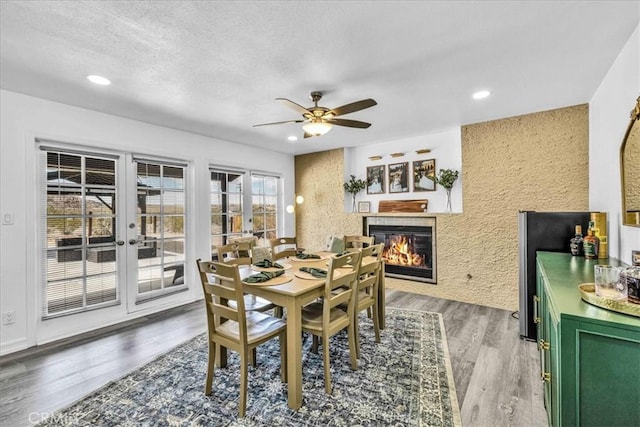 dining area featuring light wood finished floors, recessed lighting, a tile fireplace, and a textured ceiling