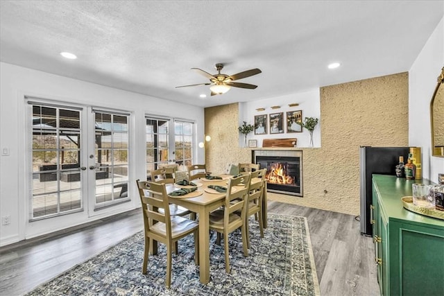 7068 Eucalyptus Ave Unit 29, Palms, CA 92277 - dining area with a tiled fireplace, french doors, ceiling fan, light wood finished floors, and recessed lighting