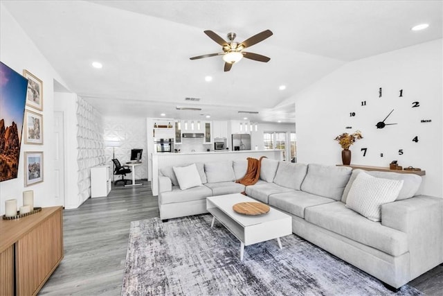 living area with visible vents, light wood-type flooring, lofted ceiling, recessed lighting, and a ceiling fan