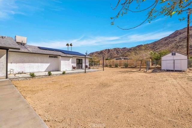 view of yard with a patio, an outbuilding, a fenced backyard, a storage unit, and a mountain view