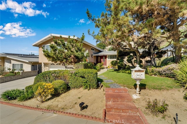 view of front facade with stucco siding, driveway, a front yard, and a garage