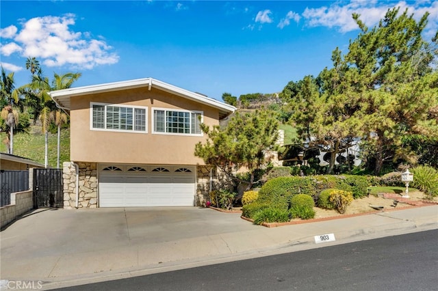 view of front of property featuring fence, an attached garage, stucco siding, concrete driveway, and stone siding