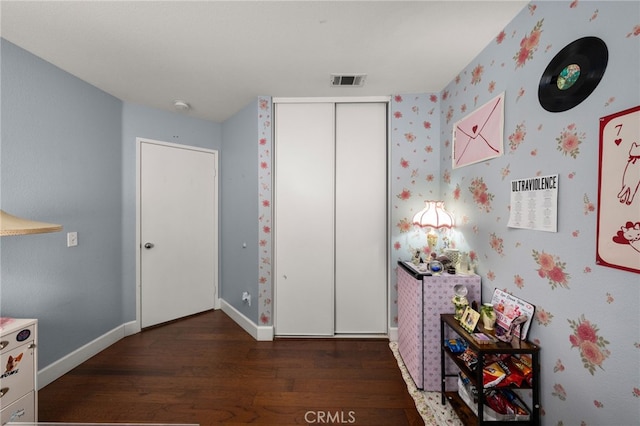 unfurnished bedroom with visible vents, wood finished floors, a closet, wallpapered walls, and baseboards