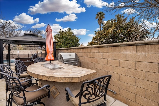 view of patio / terrace with a gazebo, an outdoor kitchen, a grill, and fence