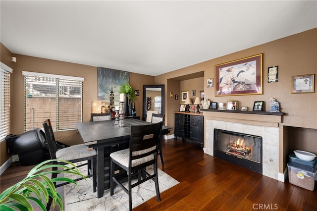 dining space featuring a fireplace, baseboards, and wood finished floors