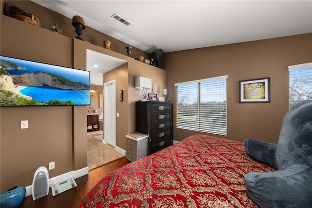 bedroom with visible vents, baseboards, and wood finished floors