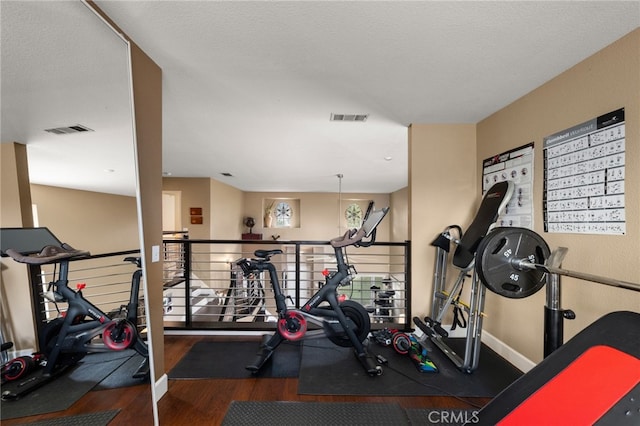 exercise room with visible vents, baseboards, and wood finished floors