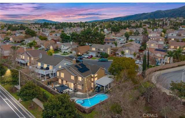 aerial view at dusk featuring a mountain view and a residential view