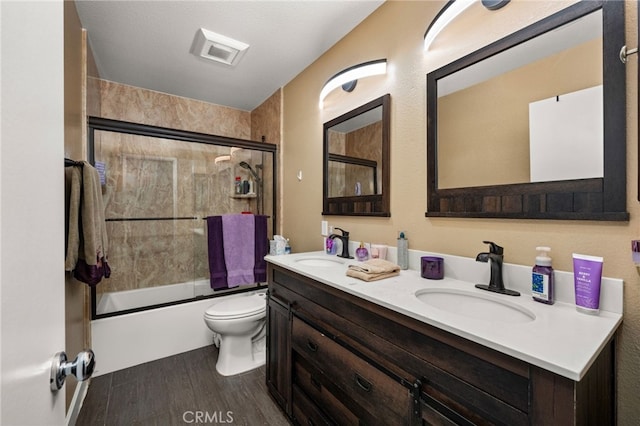 full bath featuring double vanity, wood finished floors, combined bath / shower with glass door, and a sink