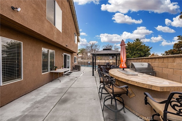 view of patio / terrace with outdoor dry bar, exterior kitchen, a gazebo, a fenced backyard, and area for grilling