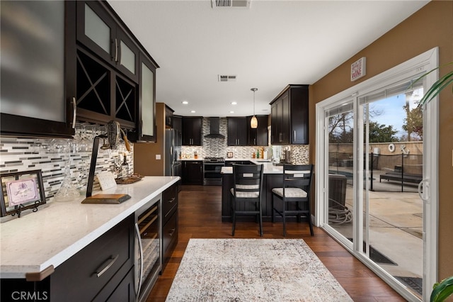 kitchen featuring visible vents, beverage cooler, decorative light fixtures, light countertops, and dark cabinets