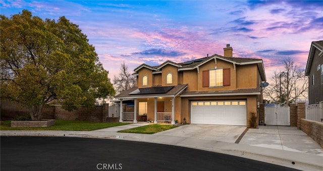 traditional home with solar panels, fence, a porch, a garage, and a gate