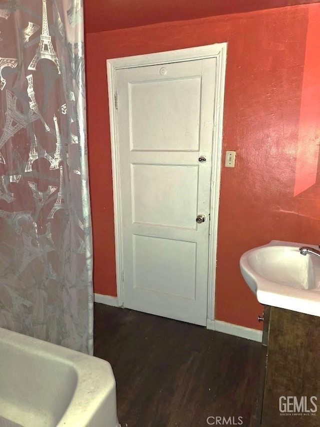 full bathroom with baseboards, a bathing tub, wood finished floors, a shower with shower curtain, and vanity