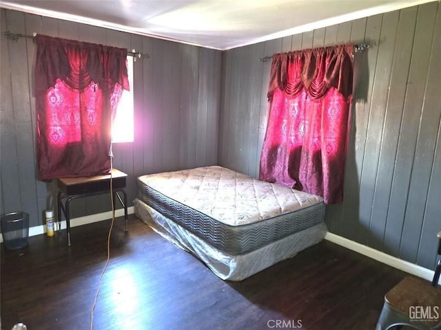 bedroom featuring wood walls, baseboards, and wood finished floors