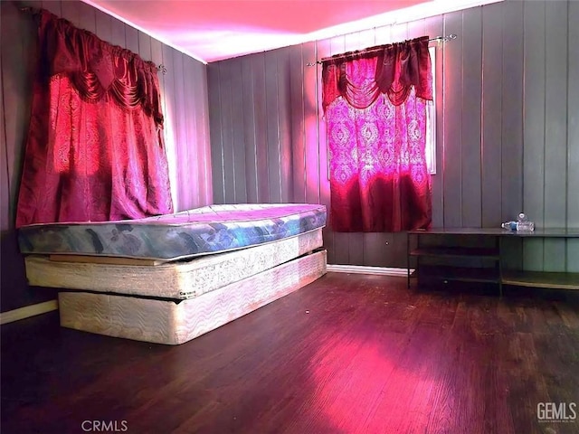 misc room with baseboards, wood finished floors, and wooden walls