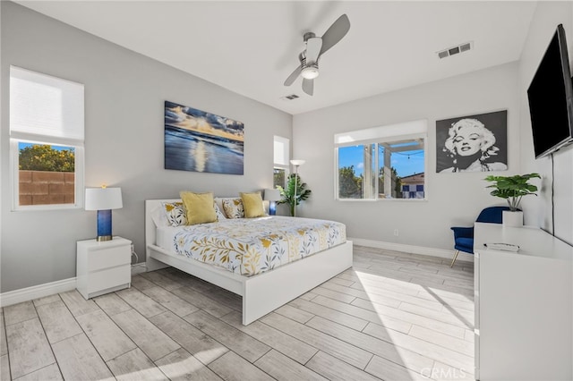 bedroom with visible vents, multiple windows, baseboards, and wood tiled floor